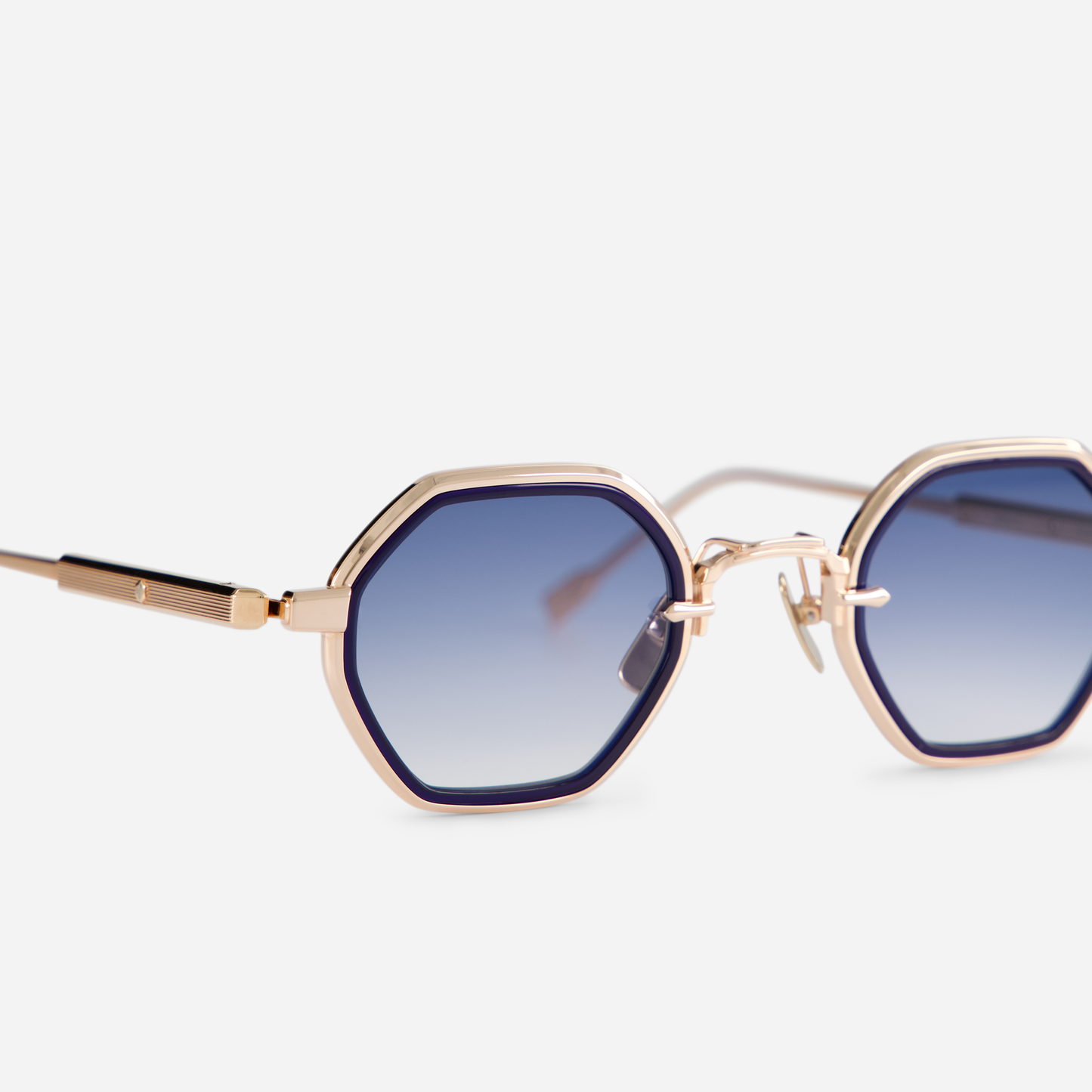 This eyewear, Arraï-T RG-1, includes a titanium frame with rose gold coating, a dark blue takiron rim insert, and gradient dark blue lenses.