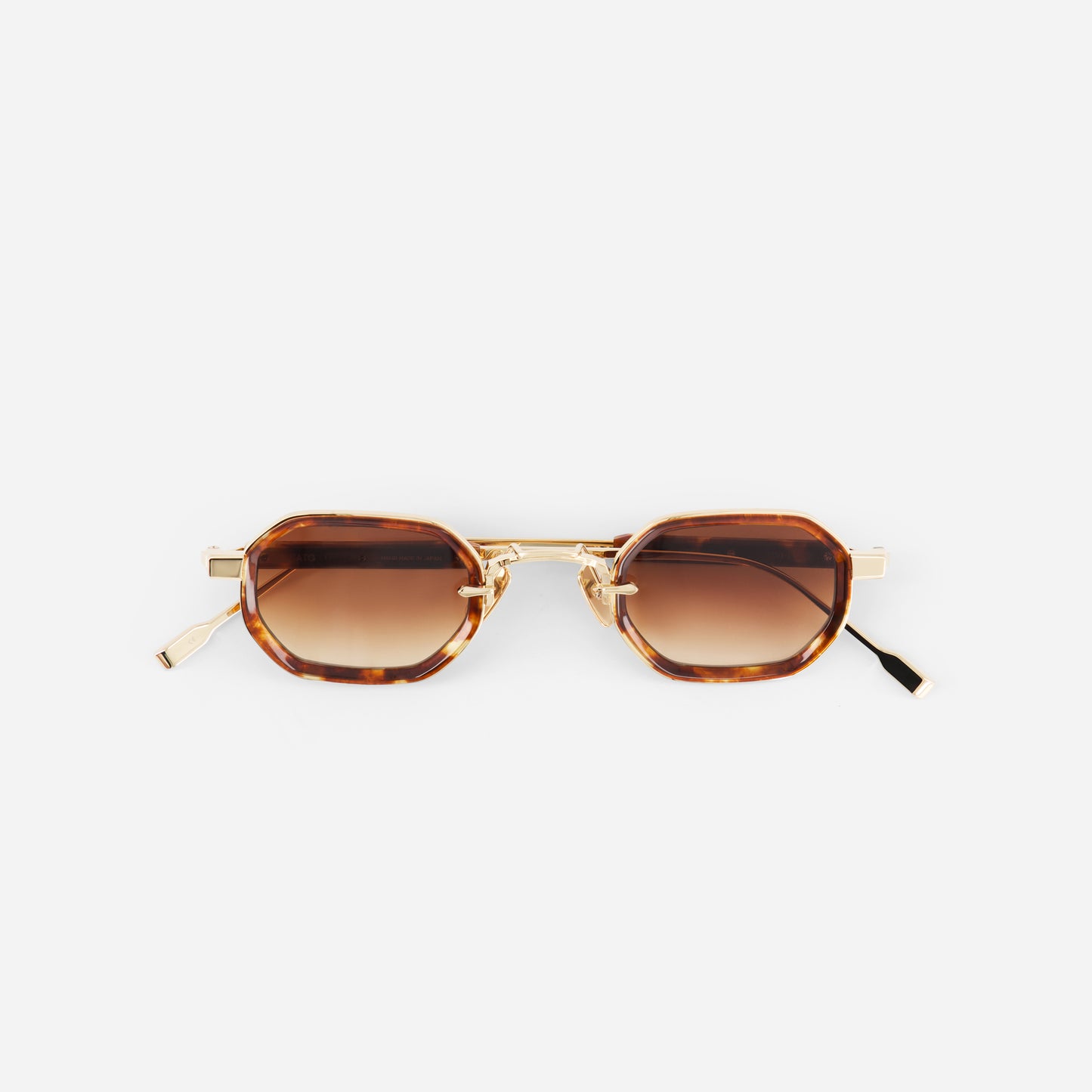 Sunglasses with brown gradient lenses and gold frame on a white background