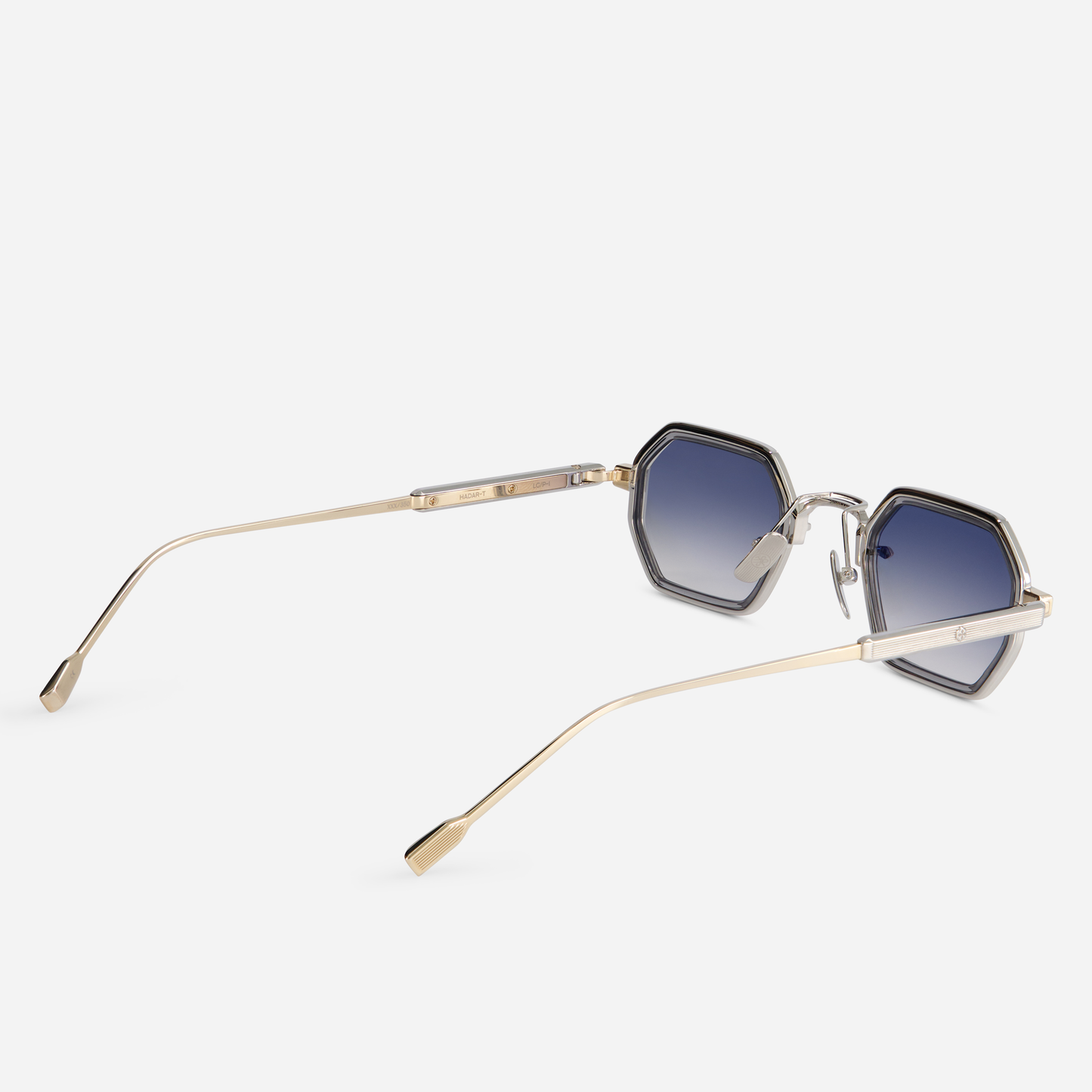 These eyeglasses offer a titanium frame with lunar gold and platinum coating. They feature a crystal grey takiron rim insert and gradient grey lenses, making up the Hadar-T LG/P-1.