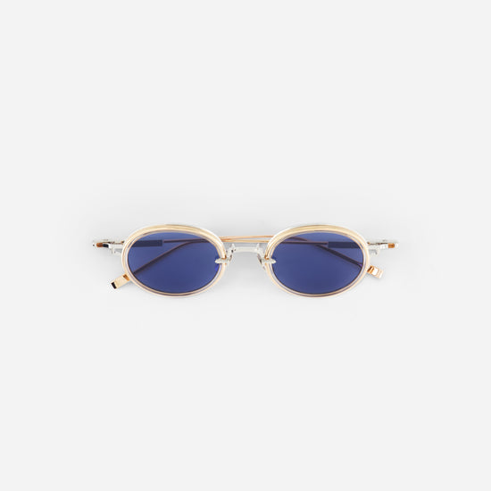 Small ovale sunglasses with gold frame and blue lenses on a white background