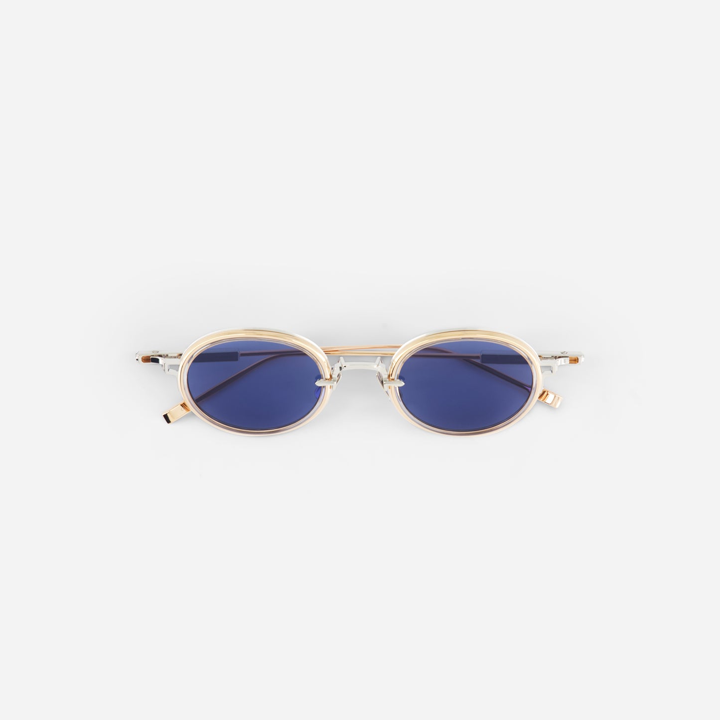 Small ovale sunglasses with gold frame and blue lenses on a white background