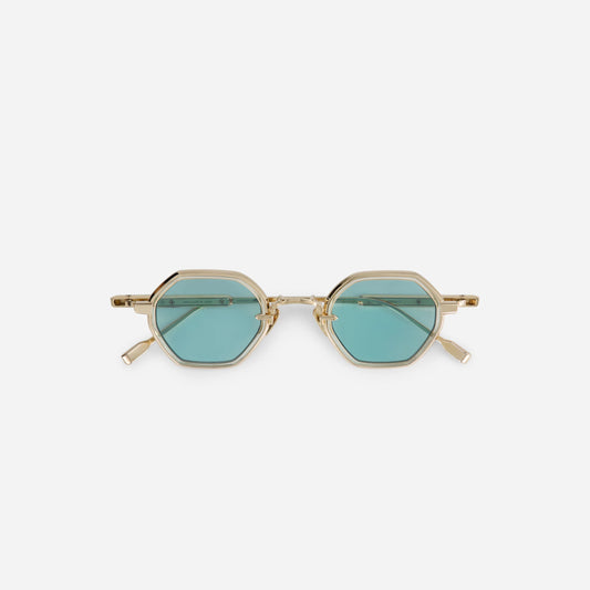 The Arraï-T LG-1 features a titanium frame with a lunar gold coating, honey yellow takiron rim insert, and turquoise lenses.