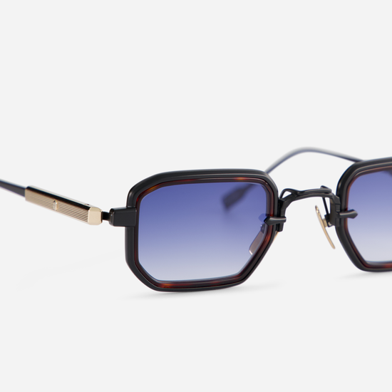 The Deneb-T B/LG-1 eyeglasses come with a titanium frame featuring black mat and lunar gold coating, along with a tortoise takiron rim insert and gradient dark blue lenses.