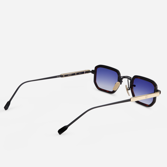 These eyeglasses offer a titanium frame with black mat and lunar gold coating. They feature a tortoise takiron rim insert and gradient dark blue lenses, making up the Deneb-T B/LG-1.
