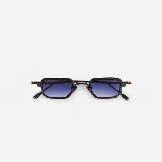 The Deneb-T B/LG-1 eyeglasses by Sato have a titanium frame with black mat and lunar gold coating. They are complemented by a tortoise takiron rim insert and gradient dark blue lenses.