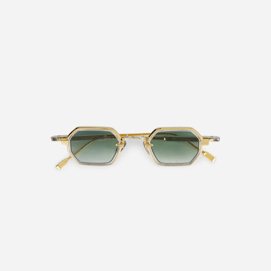 The Hadar-T YG/P-1 eyeglasses feature a titanium frame with a yellow gold coating, complemented by a crystal takiron rim insert and gradient green lenses.