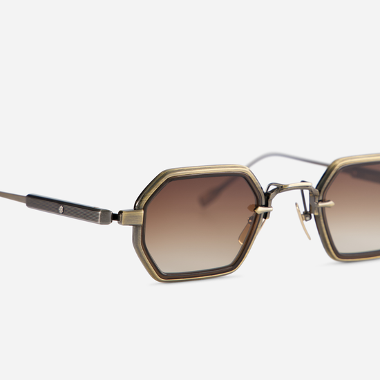 The Hadar-T AG/AS-1 eyewear has a titanium frame, antique gold, and antique silver coating, as well as a chocolate takiron rim insert and gradient brown lenses.