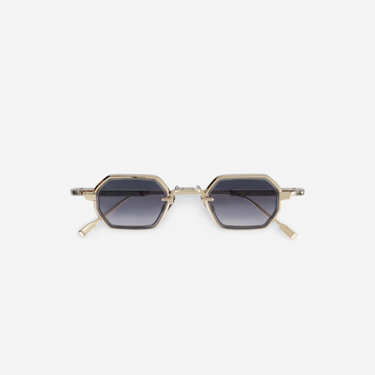 The Hadar-T LG/P-1 features a titanium frame with lunar gold and platinum coating, crystal grey takiron rim insert, and gradient grey lenses.