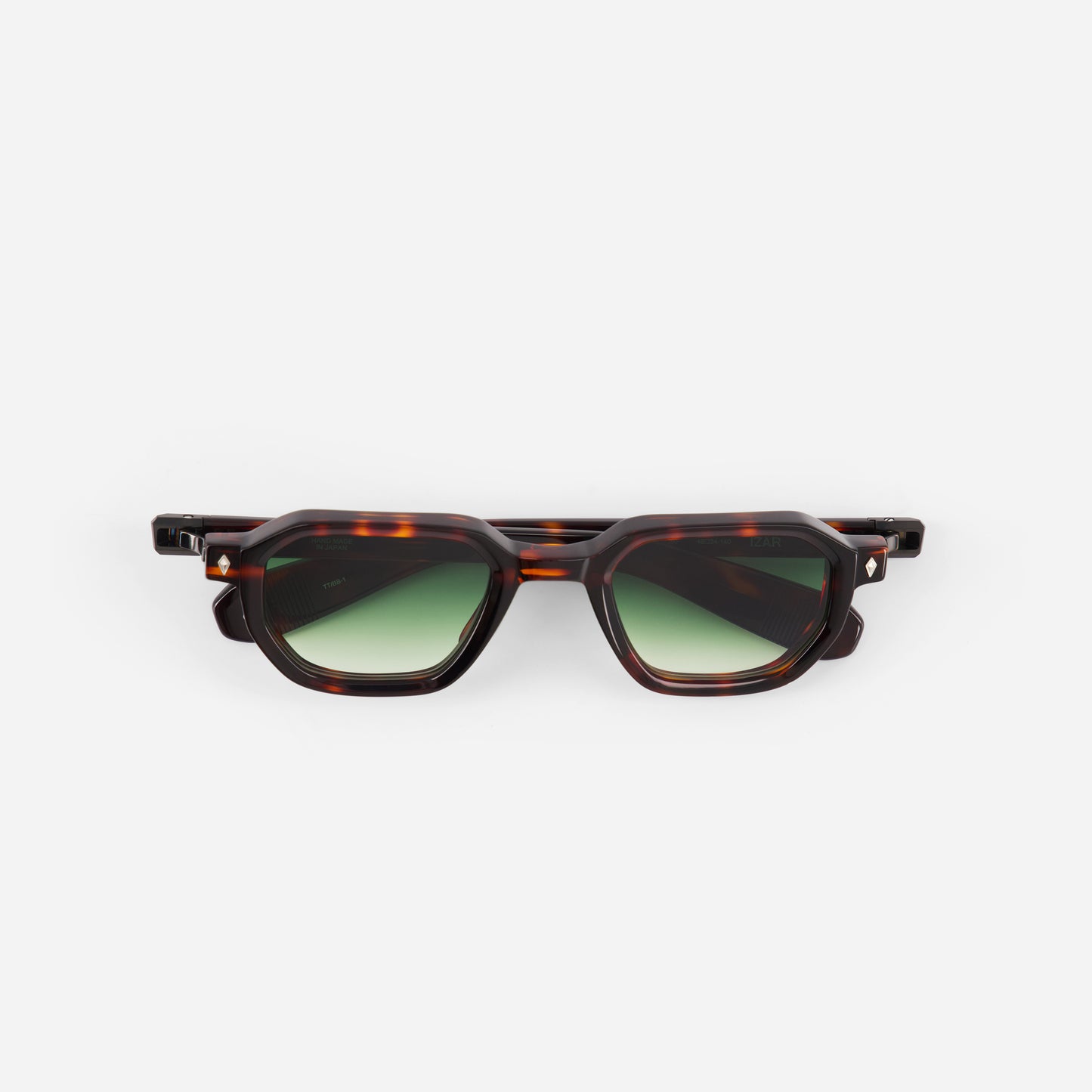 Sunglasses with tortoiseshell frame and green lenses on a white background