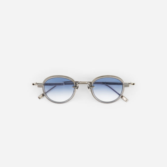 Round titanium sunglasses with gradient blue lenses on a white background
