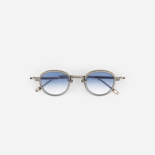 Round titanium sunglasses with gradient blue lenses on a white background