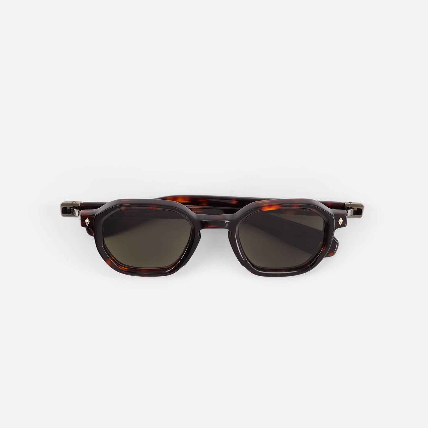 Sunglasses with tortoiseshell frame and dark green lenses on a white background