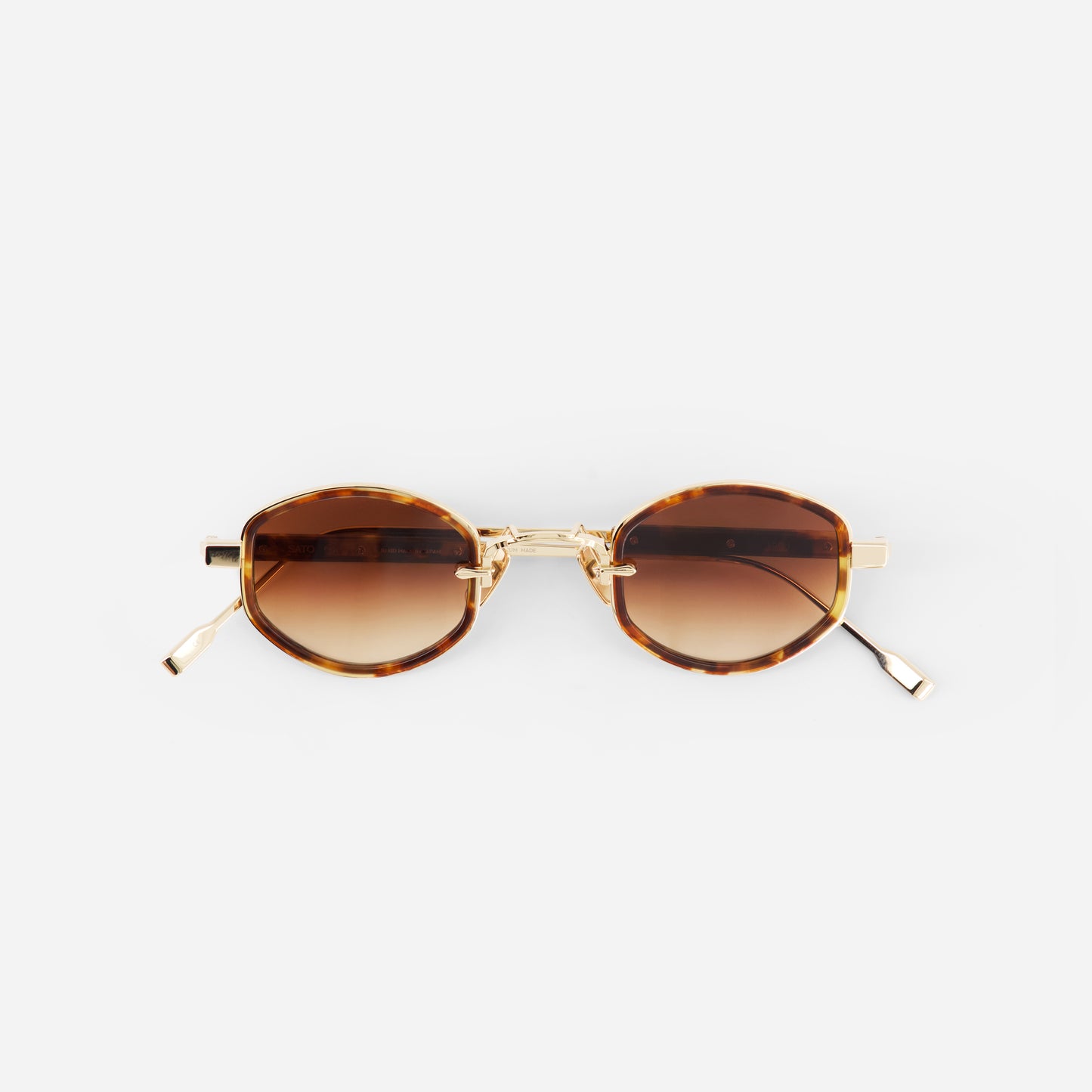 Sunglasses with brown gradient lenses and gold frame on a white background