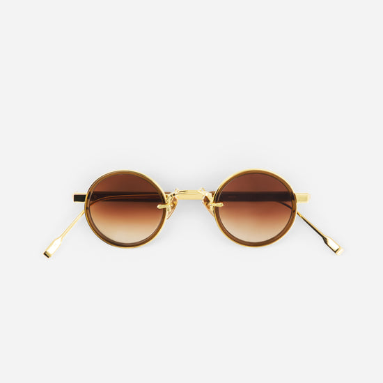 Gold-framed sunglasses with brown gradient lenses on a white background