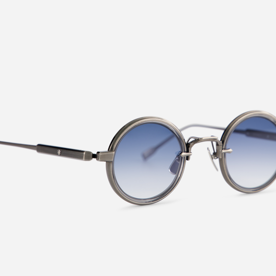 This eyewear, Rotanev-T AS-1, includes a titanium frame with an antique silver coating, a crystal grey takiron rim insert, and gradient blue lenses.