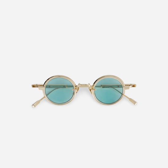 The Rotanev-T LG-1 features a titanium frame with a lunar gold coating, honey yellow takiron rim insert, and turquoise lenses.