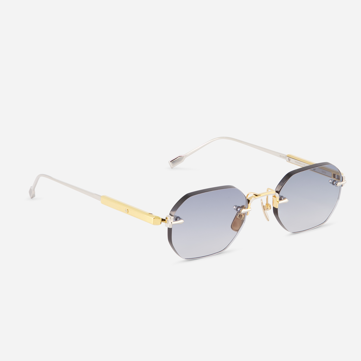 Terebellum II S703, with its uniquely rounded hexagonal rimless silhouette, adorned in yellow gold and platinum, beautifully contrasted by blue lenses.