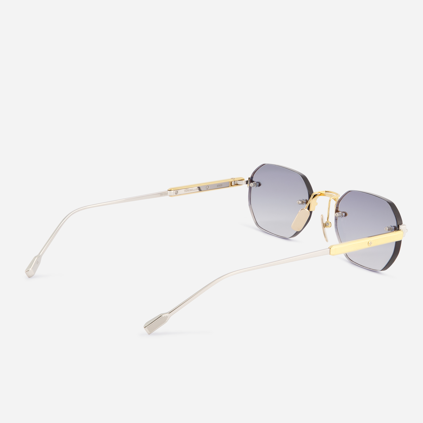 The Terebellum II S703, featuring a distinctive rounded hexagonal rimless shape, yellow gold and platinum details, and stylish blue lenses, embodies the perfect fusion of style and luxury.