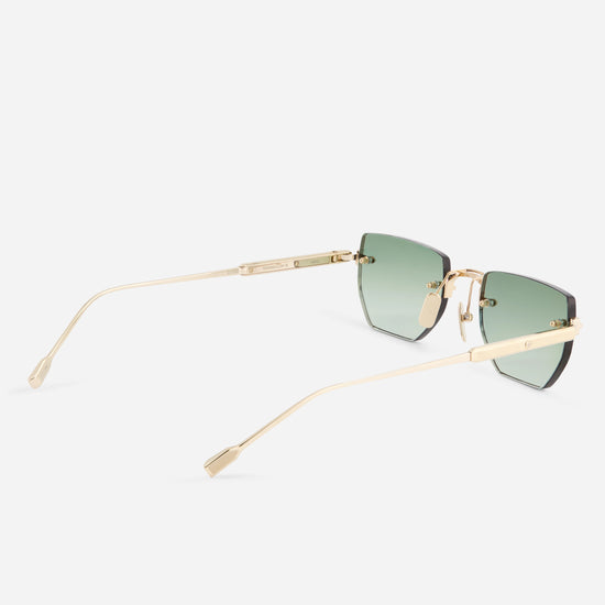 A pair of rimless square sunglasses with a gold titanium frame and green gradient lenses, shown from a side angle on a light gray background.