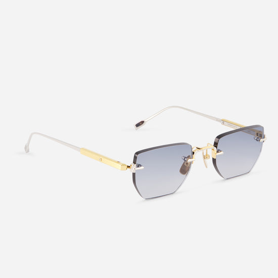 Rimless sunglasses with a gold titanium frame, silver and gold temples, and gradient gray lenses, shown on a light gray background.