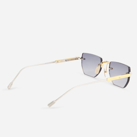 A pair of rimless square sunglasses with gradient gray lenses, gold metal bridge and temple accents, and clear temples, shown on a light gray background.