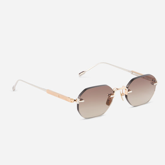 Sunglasses with rose gold and platinum titanium frame and gradient brown lenses on a white background