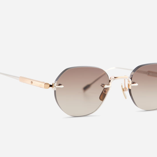 Close-up side view of rimless sunglasses with a gradient brown lens and rose gold titanium frame on a light gray background.