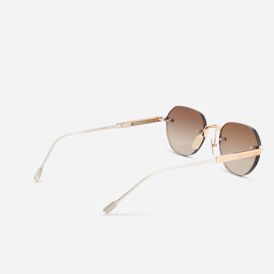 Round sunglasses with gradient brown lenses, a rose gold metal frame, and slim clear temples, shown from a three-quarters angle on a light gray background.