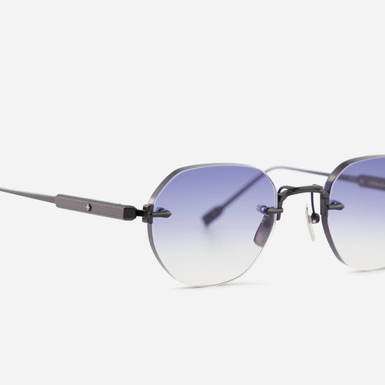 Close-up of a pair of rimless eyeglasses with a dark gray titanium frame and gradient blue-to-clear gradient lenses, shown against a light gray background.